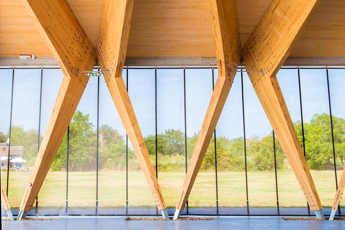 Zoom on the V-shaped wooden poles of the Teich covered hall realized by the agency Bulle Architectes.