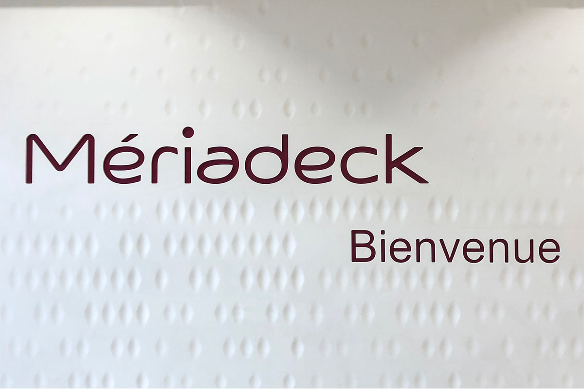 Signalétique sur mur blanc texturé de formes losanges réalisée par l'agence Bulle Architectes au centre commercial Meriadeck à Bordeaux.