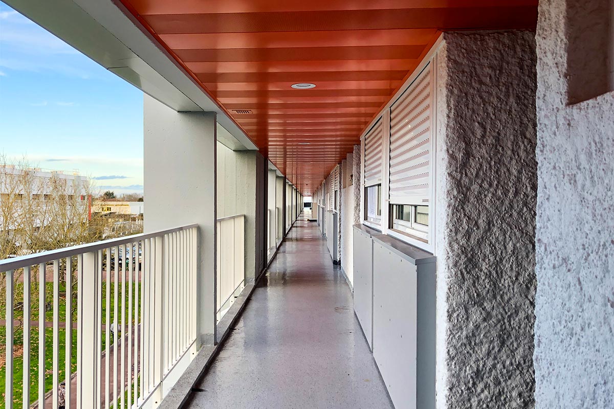 Couloir extérieur menant aux appartements de la résidence Grand Caillou réhabilitée par Bulle Architectes à Bordeaux.