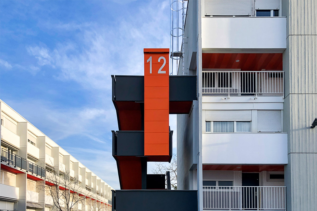 Détail du numéro de bâtiment et des escaliers extérieurs de la résidence Grand Caillou à Eysines réhabilitée par l'agence bordelaise Bulle Architectes.