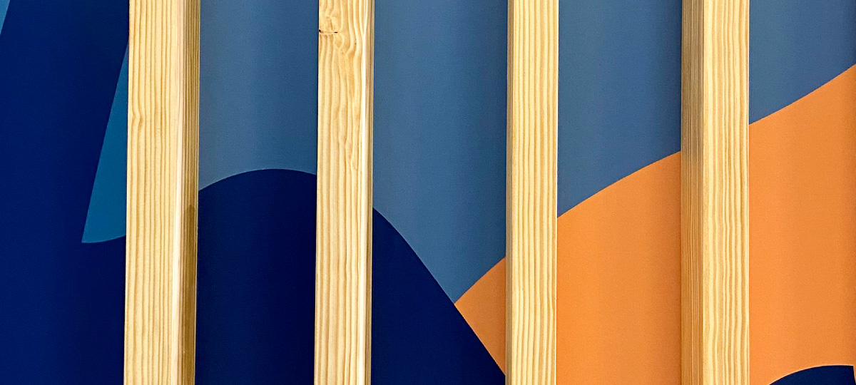 Zoom sur la fresque colorée et les tasseaux en bois présents dans les nouveaux vestiaires du lycée Nord Bassin Simone Veil à Andernos et rénovés par l'agence bordelaise Bulle Architectes.
