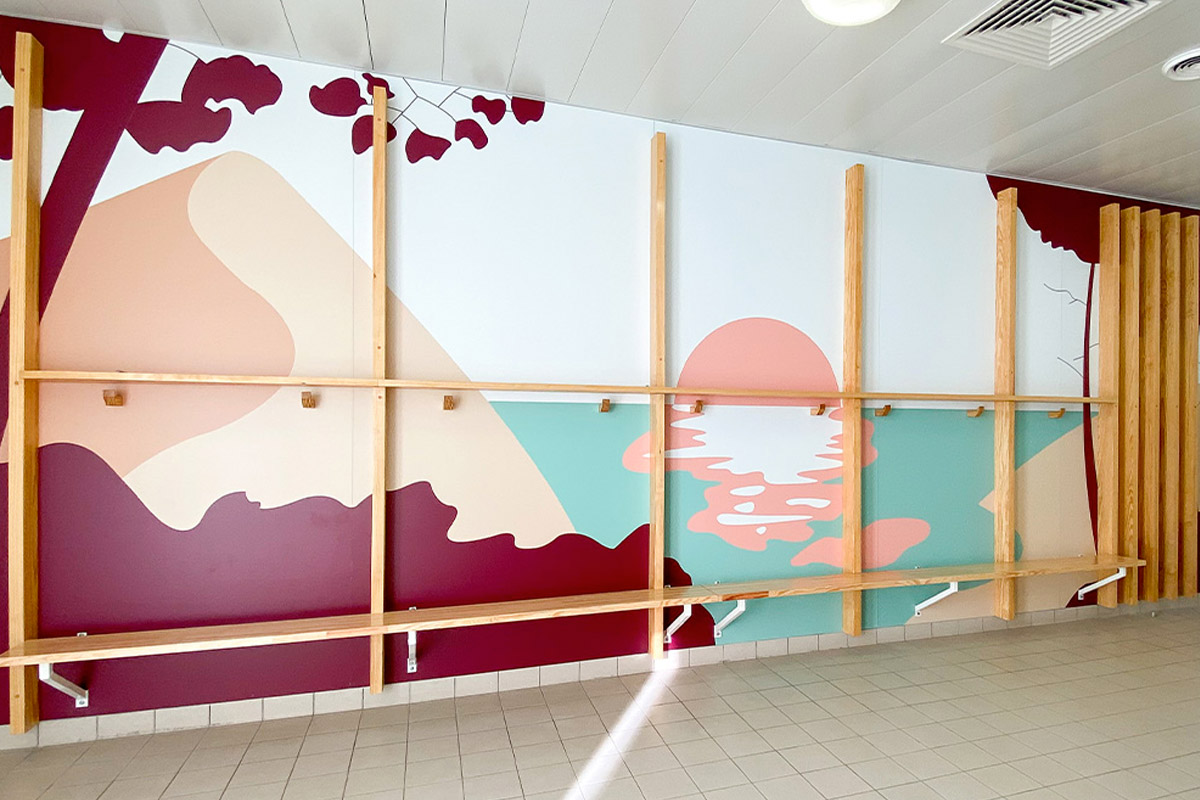 Overall view of the colorful fresco and wooden benches in the new girls' locker room of the Lycée Nord Bassin Simone Veil in Andernos renovated by the Bordeaux agency Bulle Architectes.