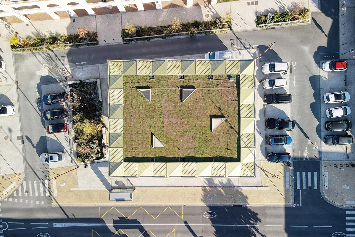 Vue aérienne de la globalité de la halle réalisée au Haillan par l'agence Bordelaise Bulle Architectes et révélant un toit végétalisé ainsi que des facettes en zinc doré
