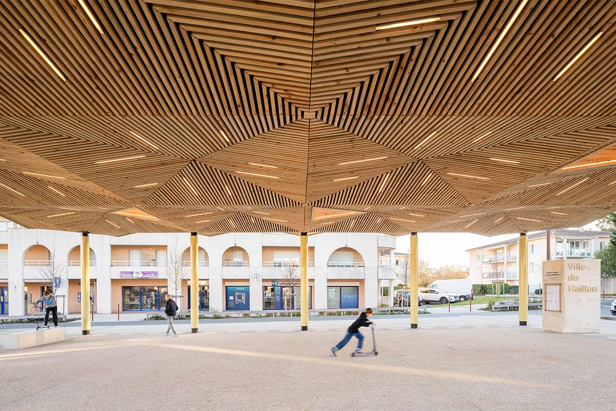 View from the underside of the hall towards the shops revealing the play of facets of the wooden underside of the hall built in Haillan by the Bordeaux agency Bulle Architectes.